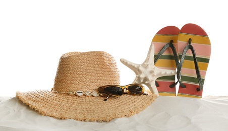Different beach accessories on sand against white background