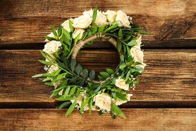 Photo of Wreath made of beautiful flowers on wooden table, top view