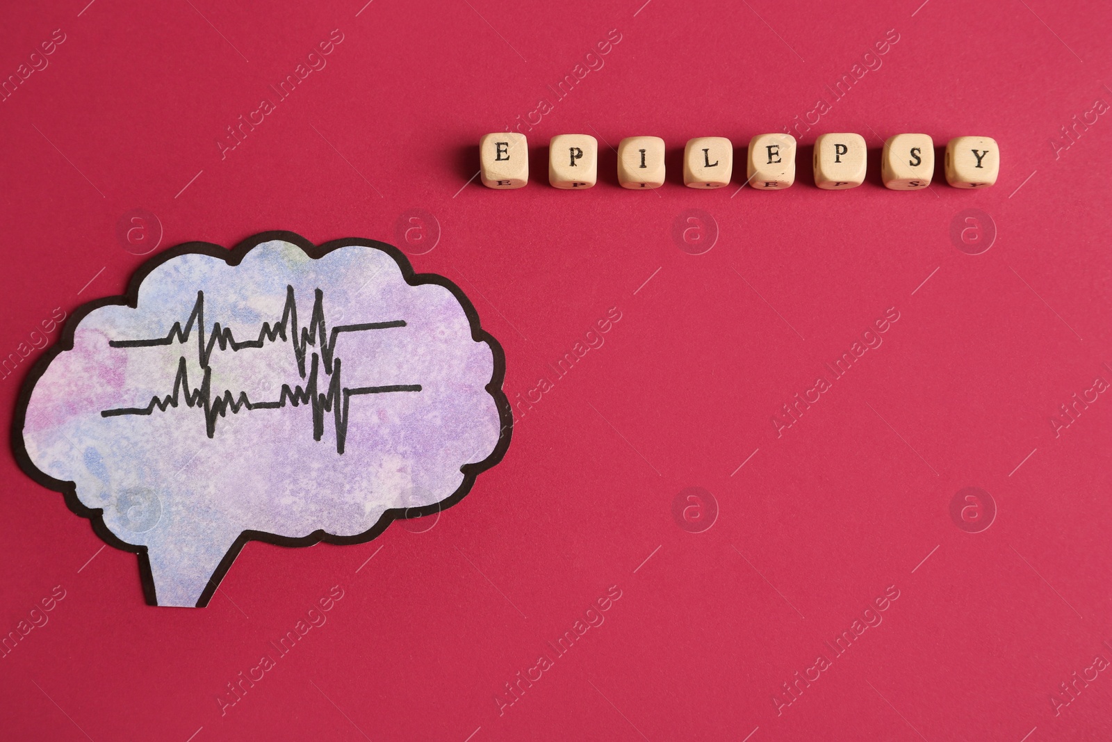 Photo of Human brain cutout with pulse lines near word Epilepsy made of wooden cubes on crimson background, flat lay. Space for text