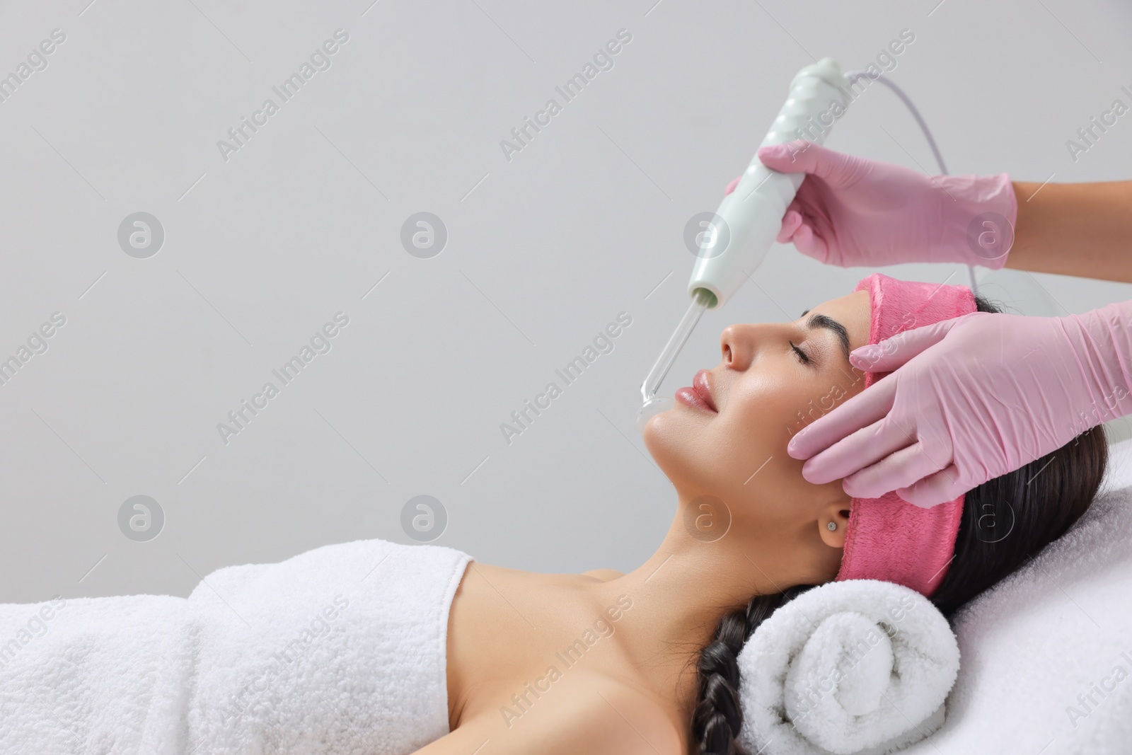 Photo of Young woman undergoing face rejuvenation procedure with darsonval in salon, space for text