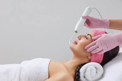 Photo of Young woman undergoing face rejuvenation procedure with darsonval in salon, space for text