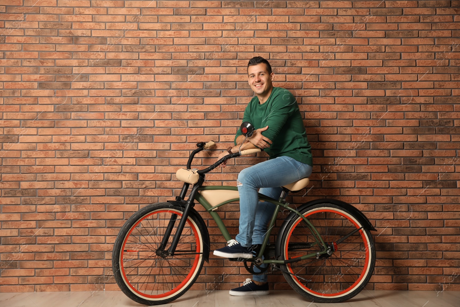 Photo of Portrait of handsome young man with bicycle near brick wall