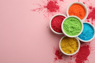 Colorful powders in bowls on pink background, flat lay with space for text. Holi festival celebration