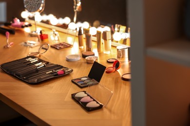 Photo of Different makeup products and brushes on wooden table indoors