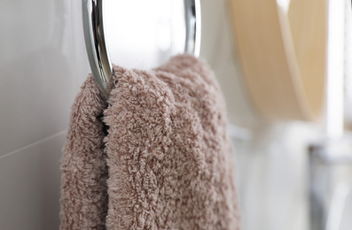 Photo of Holder with clean towel on light wall in bathroom, closeup