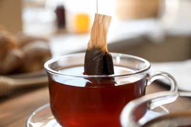 Photo of Tea bag in glass cup on table indoors, closeup