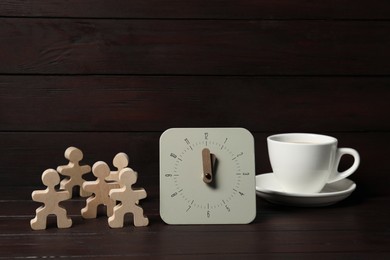 Photo of Alarm clock, human figures and cup on wooden table. Business lunch concept