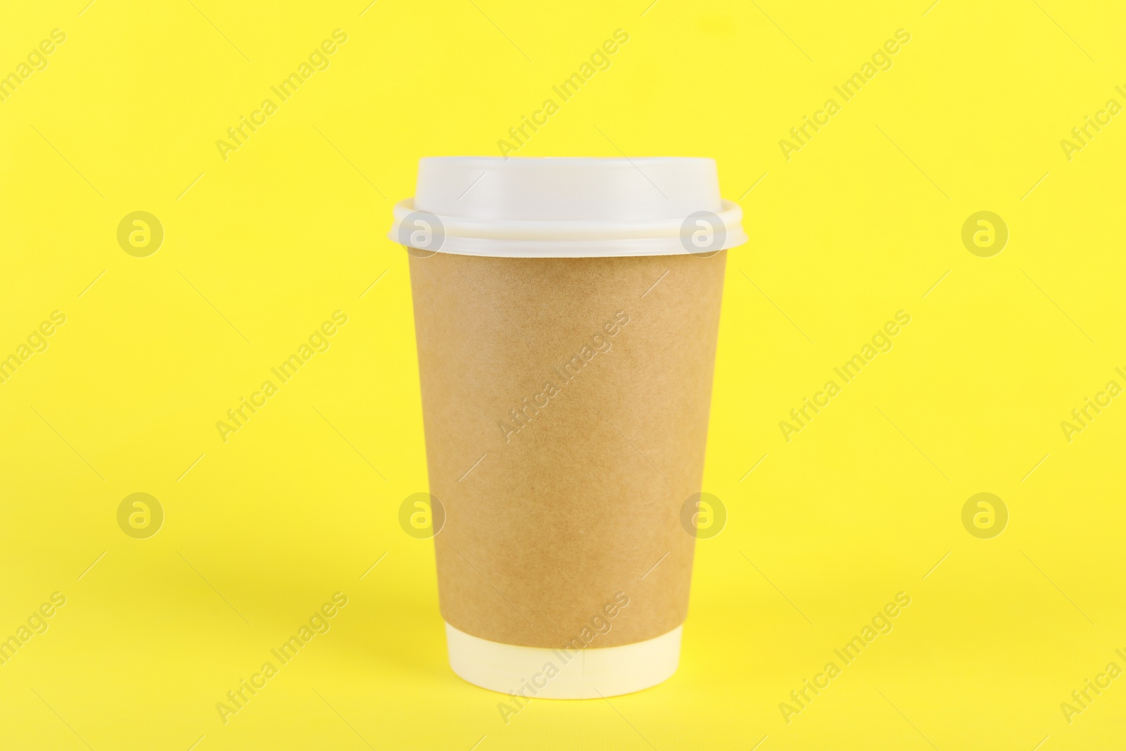 Photo of Paper cup with plastic lid on yellow background. Coffee to go