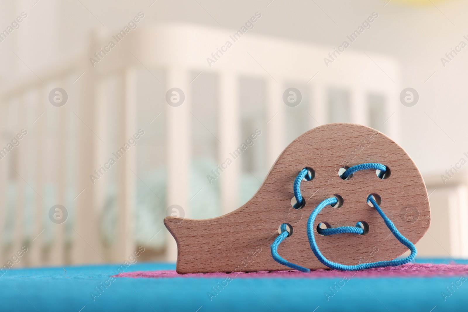 Photo of Motor skills development. Wooden lacing toy on color mat indoors, space for text