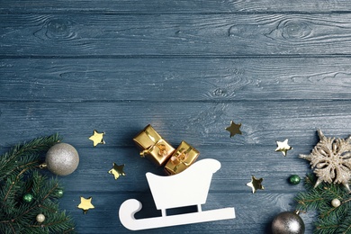 Photo of Flat lay composition with sleigh, fir tree branches and gift boxes on grey wooden table. Space for text