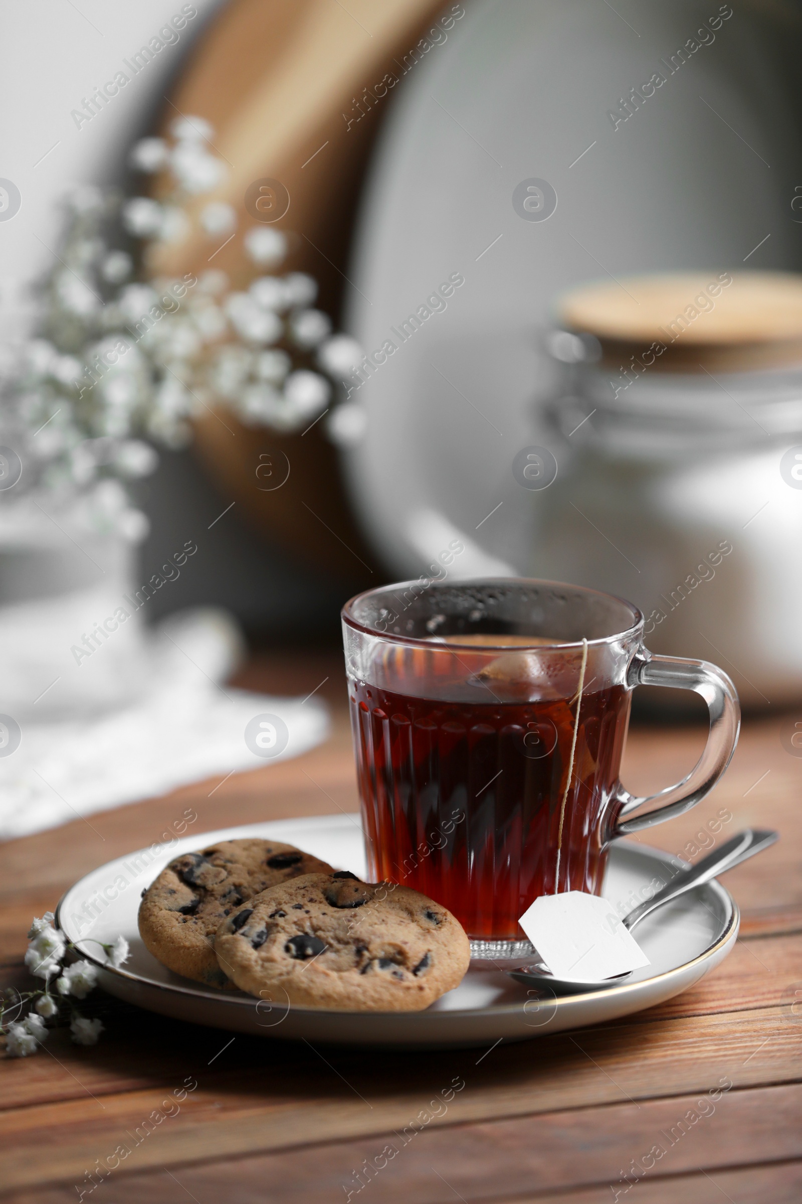 Photo of Cup of freshly brewed tea and delicious cookies on wooden table, space for text