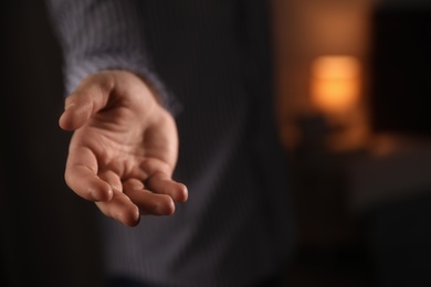 Photo of Man offering helping hand on blurred background, closeup. Space for text