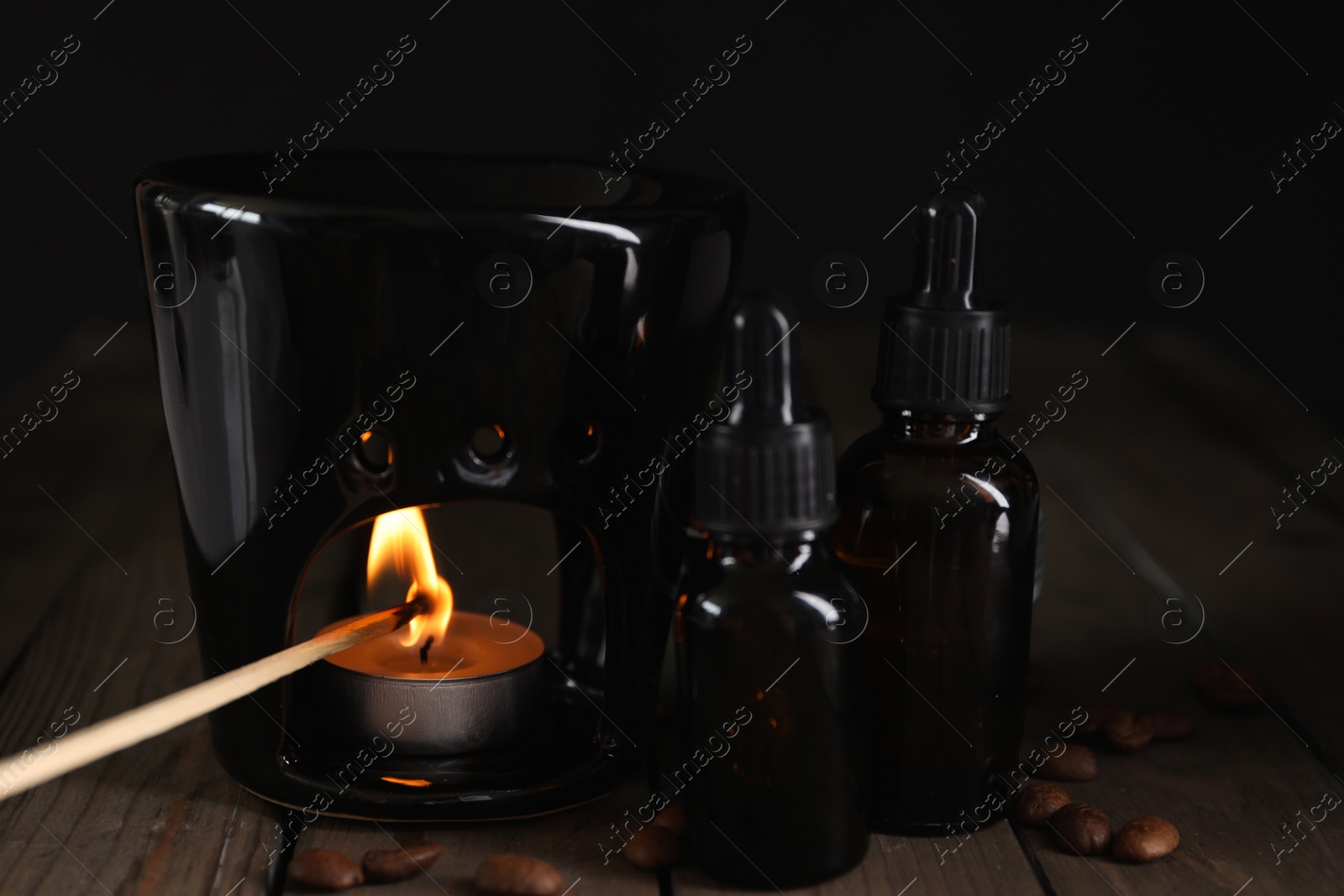 Photo of Lighting aroma lamp and coffee essential oil on wooden table