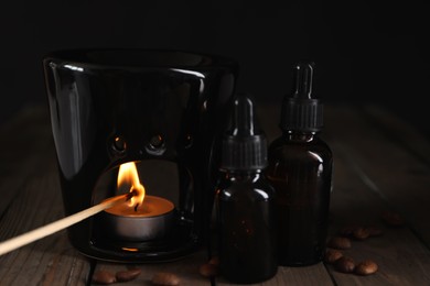 Photo of Lighting aroma lamp and coffee essential oil on wooden table
