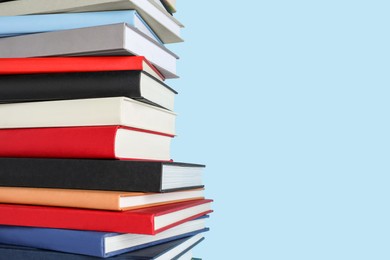 Photo of Stack of different books on light blue background, space for text