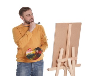 Photo of Man painting with brush on easel against white background. Young artist