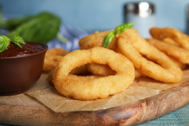 Photo of Fried onion rings served on blue wooden table, closeup