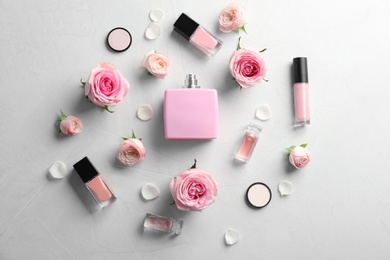 Flat lay composition with bottles of perfume, cosmetics and roses on grey background