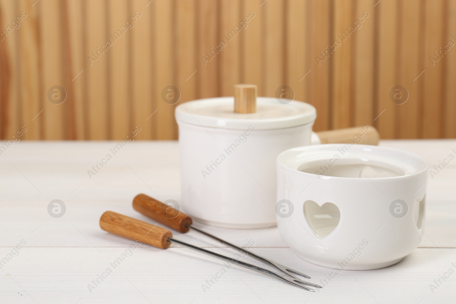 Photo of Fondue set on white wooden table, space for text