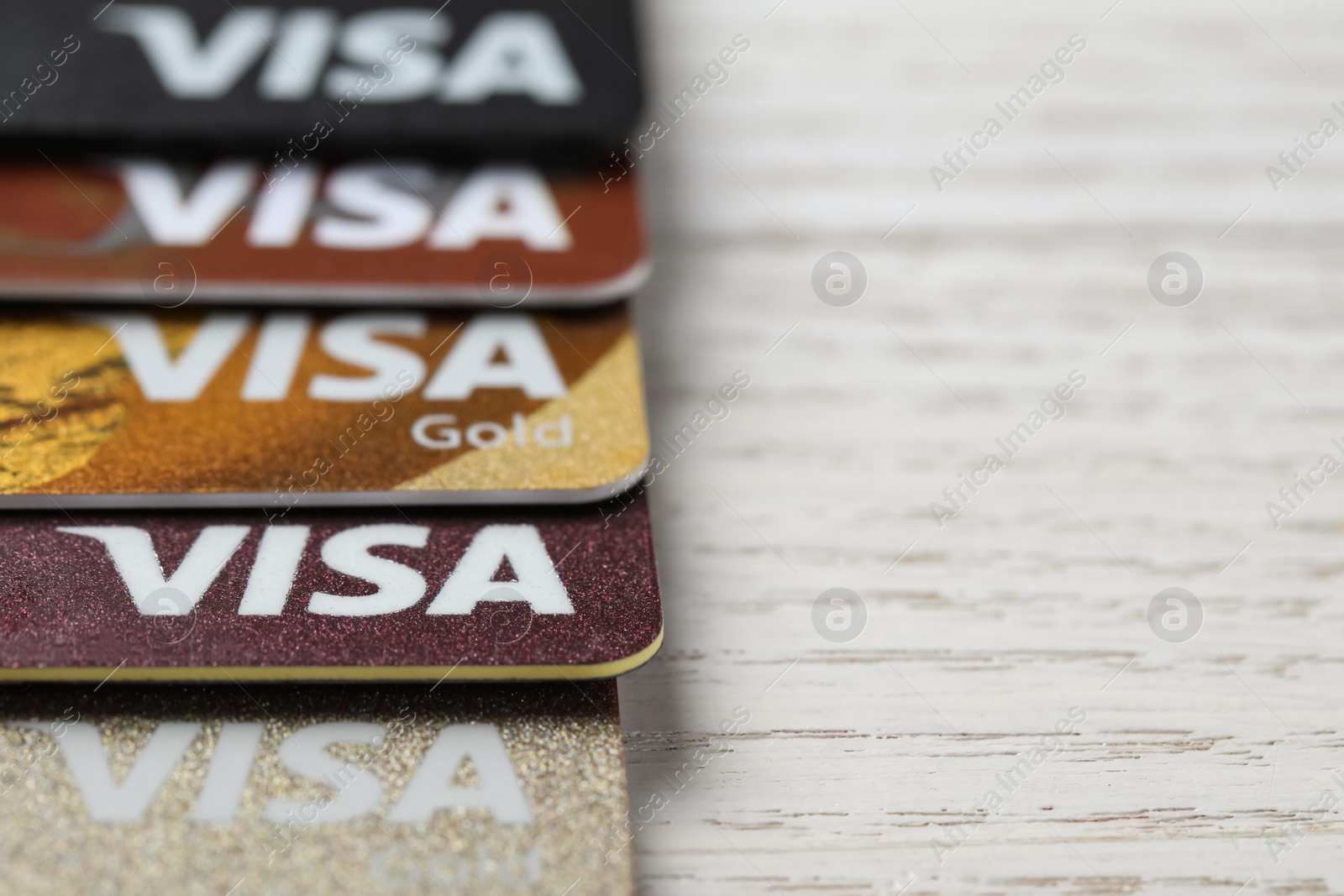 Photo of MYKOLAIV, UKRAINE - FEBRUARY 22, 2022: Visa credit cards on white wooden table, closeup. Space for text