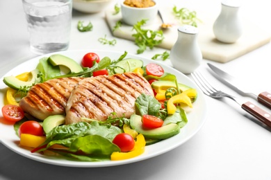 Tasty grilled chicken fillets with vegetables on light grey table, closeup