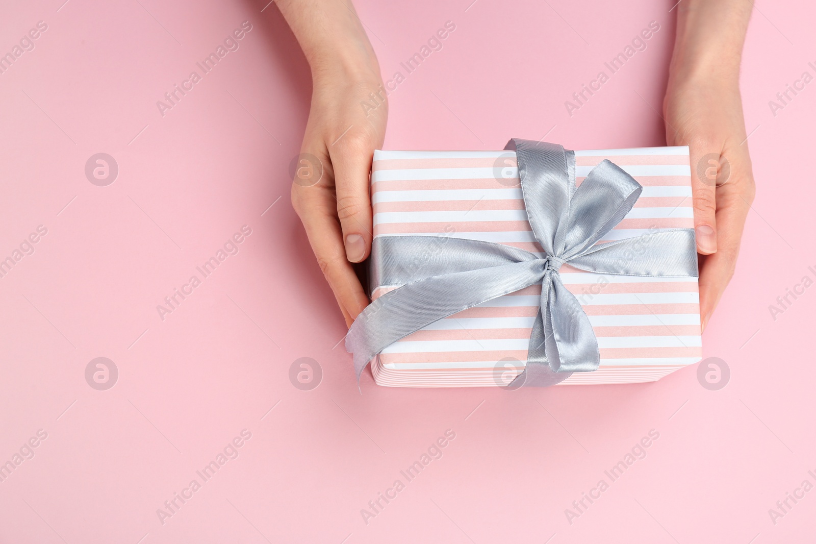 Photo of Young woman holding beautiful gift box on color background, top view