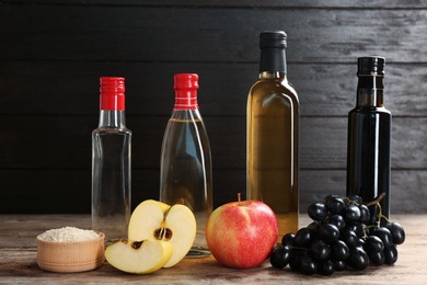 Photo of Composition with different kinds of vinegar and ingredients on wooden table