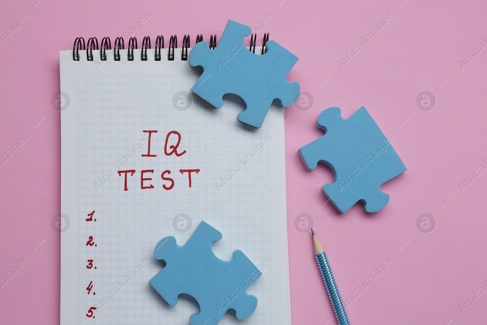 Photo of Notepad with text IQ Test, pencil and puzzle pieces on pink background, flat lay