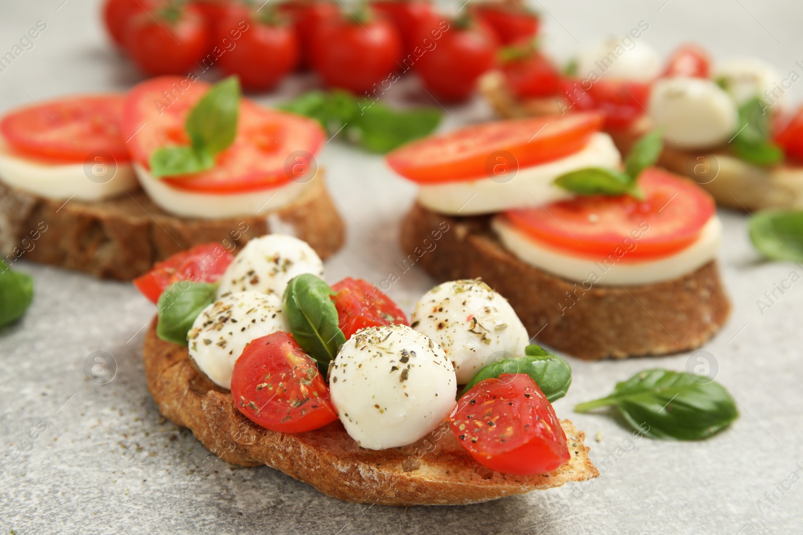 Photo of Delicious sandwiches with mozzarella, fresh tomatoes and basil on light grey table