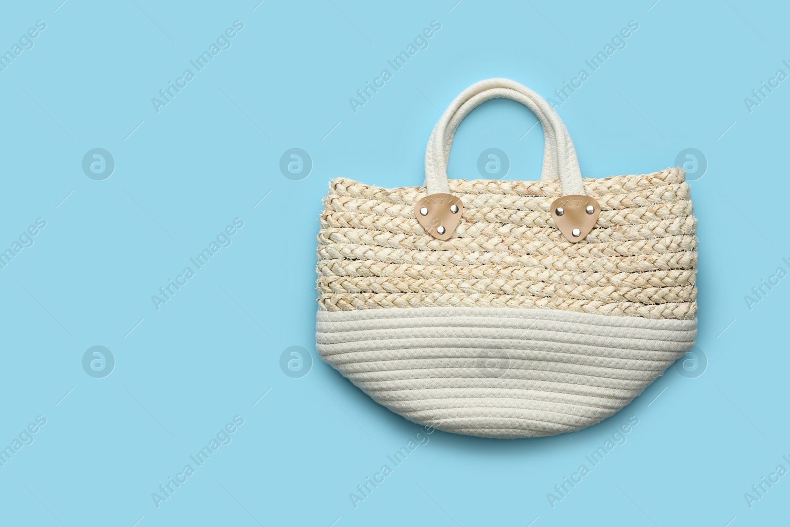 Photo of Elegant woman's straw bag on light blue background, top view. Space for text