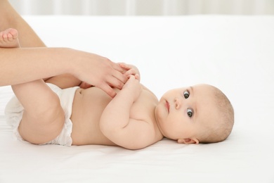 Mother with her cute child on bed indoors. Baby massage and exercises