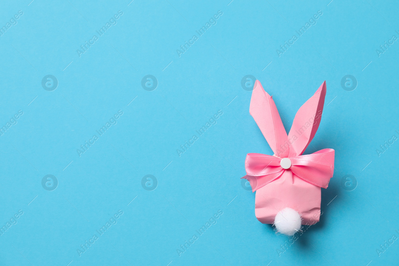 Photo of Creative Easter bunny gift bag on color background, top view with space for text