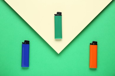 Photo of Stylish small pocket lighters on color background, flat lay