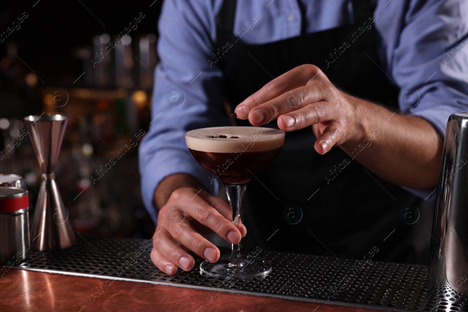 Photo of Bartender preparing Espresso Martini in bar, closeup. Alcohol cocktail