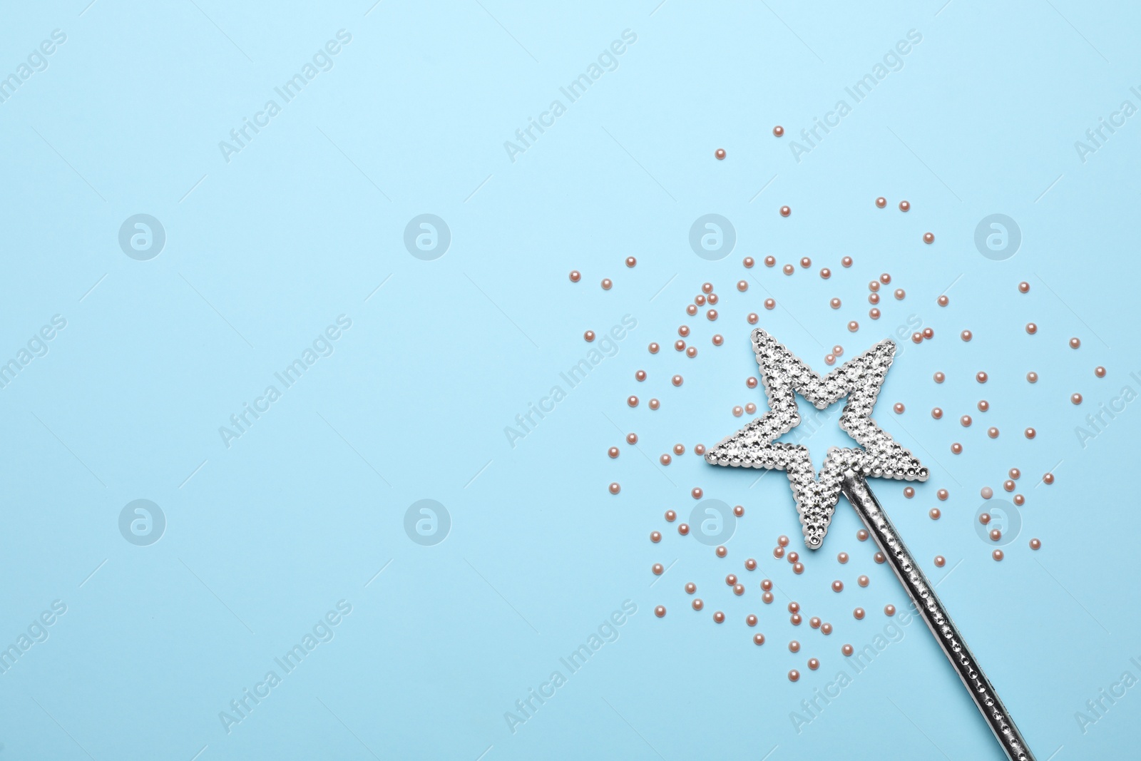 Photo of Beautiful silver magic wand and confetti on light blue background, flat lay. Space for text