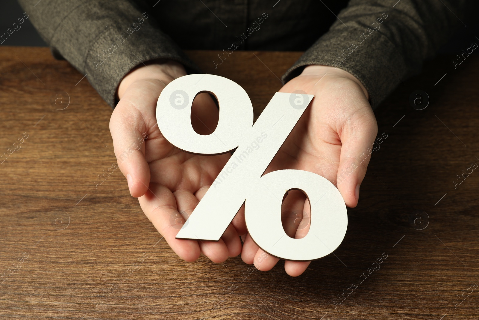 Photo of Man holding percent sign at wooden table, closeup