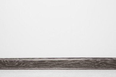 Black wooden plinth on laminated floor near white wall indoors