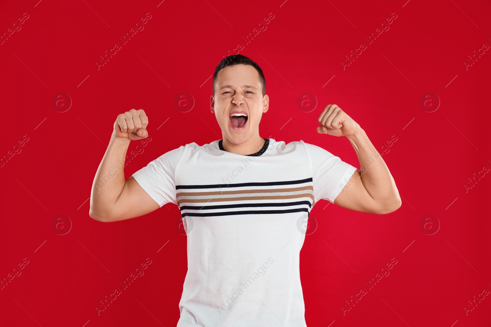 Photo of Emotional young man posing on red background