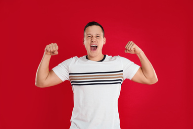 Emotional young man posing on red background