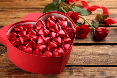 Box with heart shaped chocolate candies on wooden table