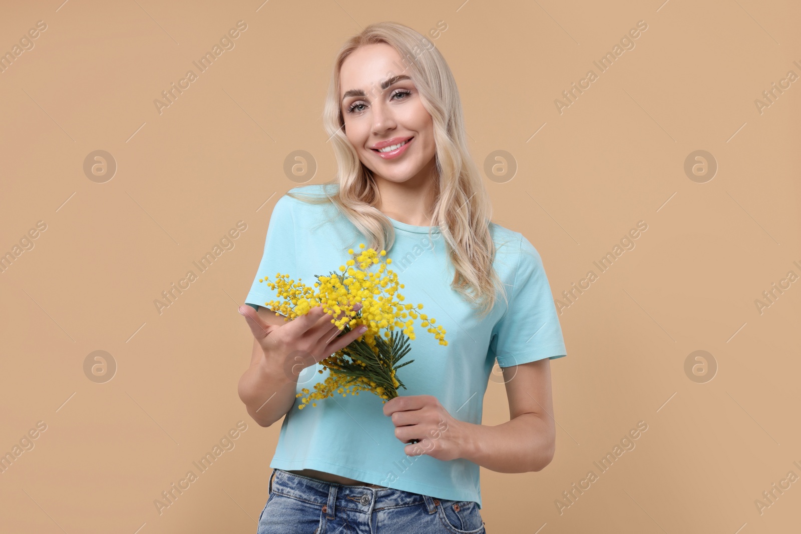 Photo of Happy young woman with beautiful bouquet on beige background