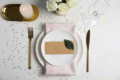 Elegant festive table setting with blank card on white background, flat lay