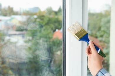 Woman painting window frame at home, closeup