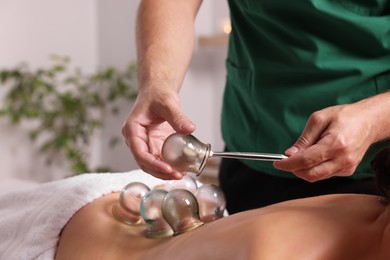 Photo of Therapist giving fire cupping treatment to patient indoors, closeup