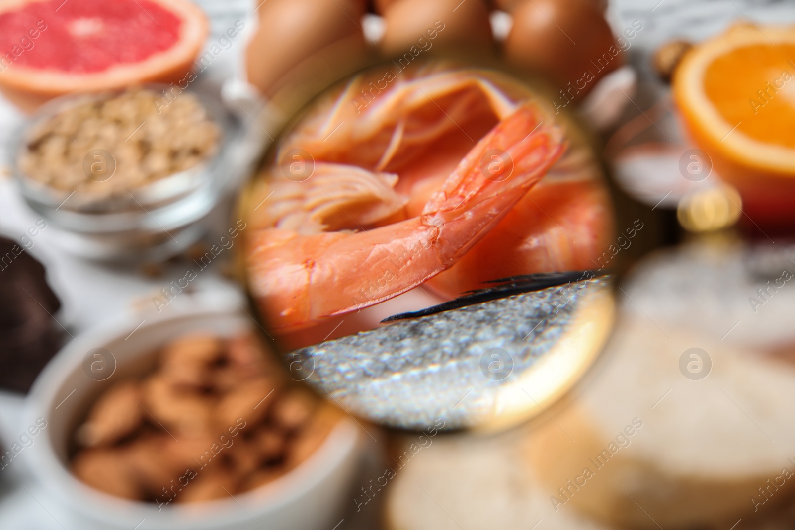 Photo of Different products with magnifier focused on shrimps and fish, closeup. Food allergy concept