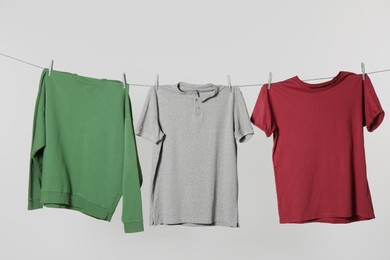 Photo of Different shirts drying on laundry line against light background