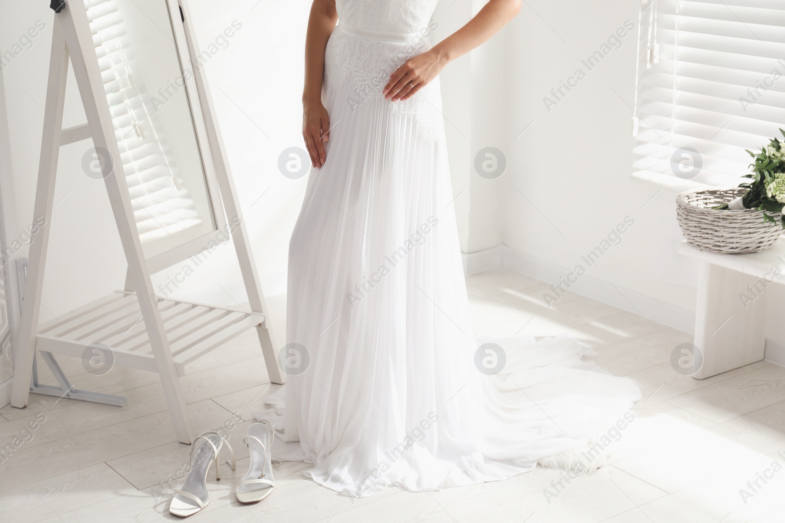 Photo of Young bride in beautiful wedding dress near mirror indoors, closeup