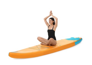 Photo of Happy woman practicing yoga on orange SUP board against white background