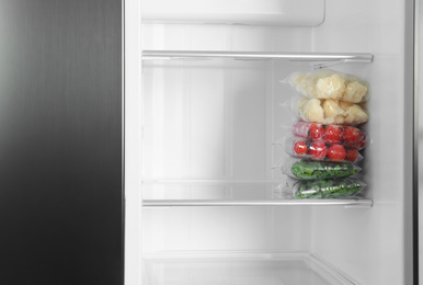 Plastic bags with different frozen vegetables in refrigerator