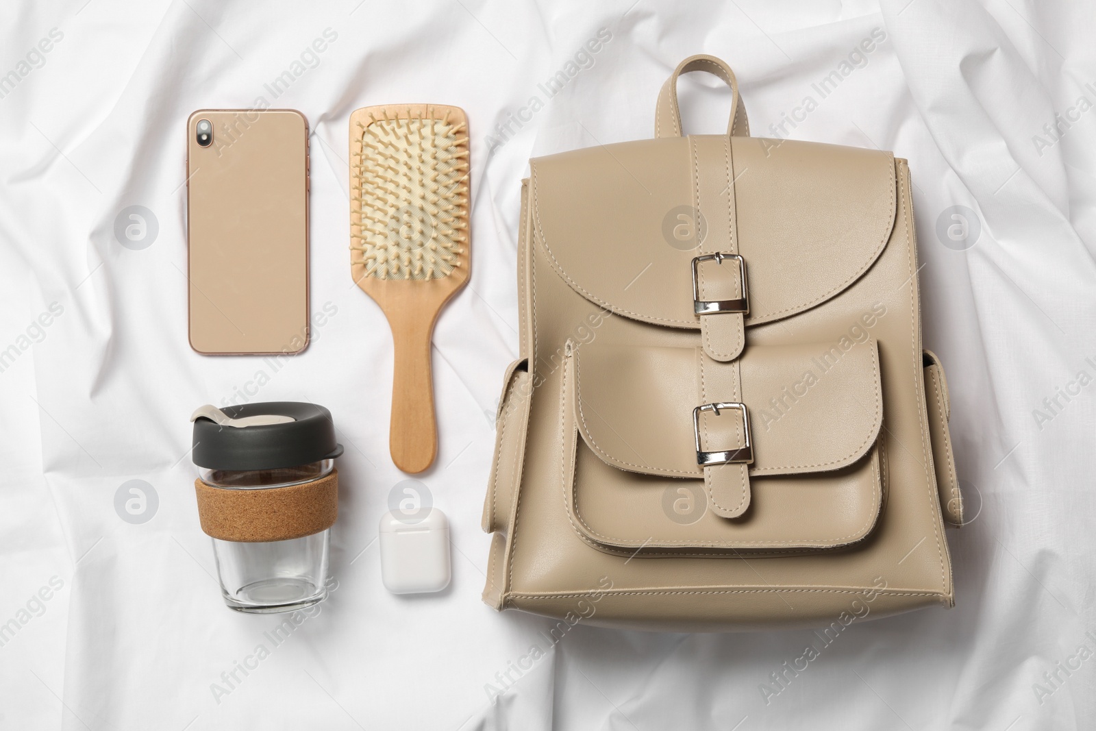 Photo of Stylish urban backpack and different items on white fabric, flat lay